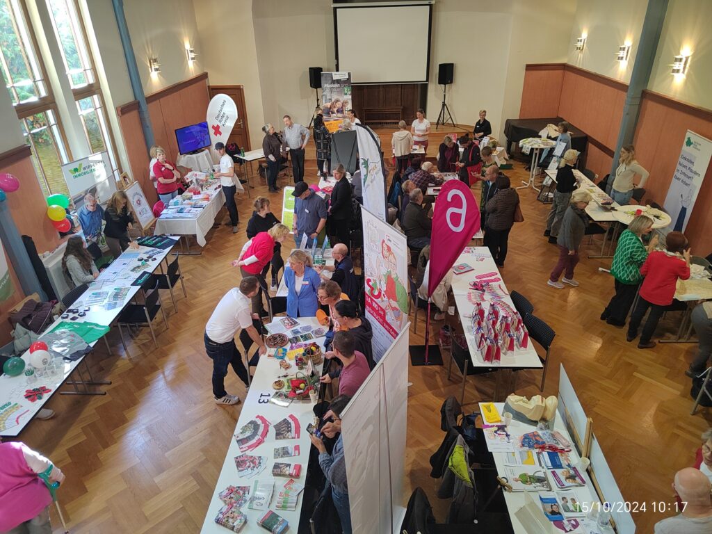 Eine Aufnahme des Veranstaltungssaals in Vogelperspektive. Der Saal steht voller Informationsstände. Oben rechts ist auch der Stand des Digitalen Engel Thüringen zu sehen.