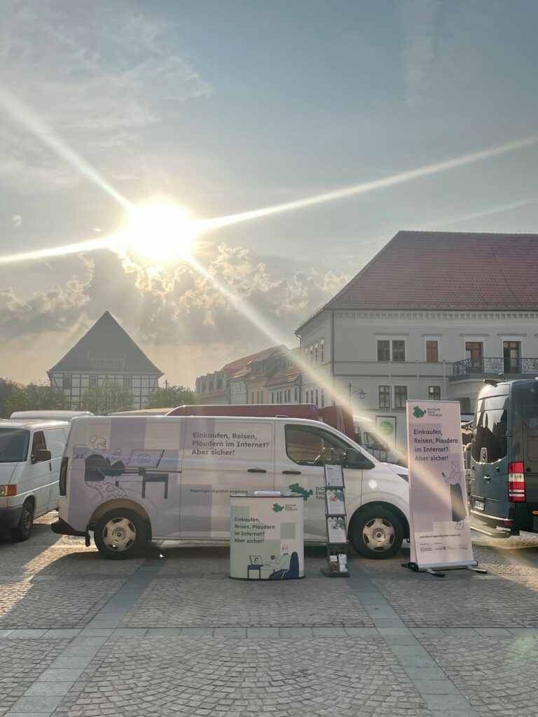 Auto des Digitalen Engel Thüringen mit Informationsstand. Im Hintergrund sind einige Häuser und die Sonne strahlt