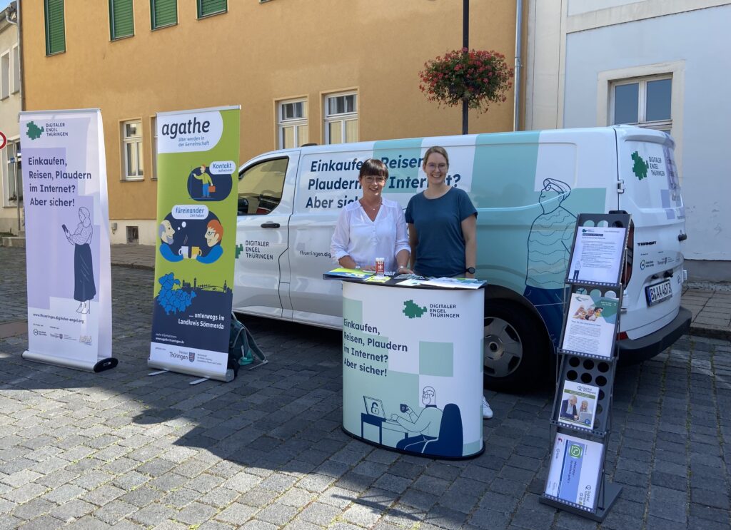 Auto des Digitalen Engel Thüringen mit Informationsstand. Zwei Personen lächeln in die Kamera.
