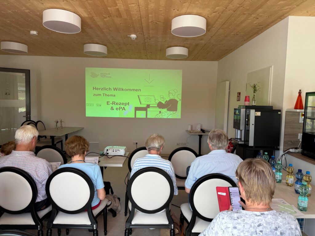 Eine Gruppe älterer Menschen sind von hinten zu sehen, wie sie auf eine Präsentation vor ihnen schauen.