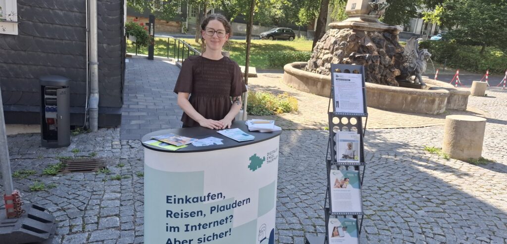 Sophie steht am Stand der digitalen Engel Thüringen auf einem Platz mit Pflastersteinen.